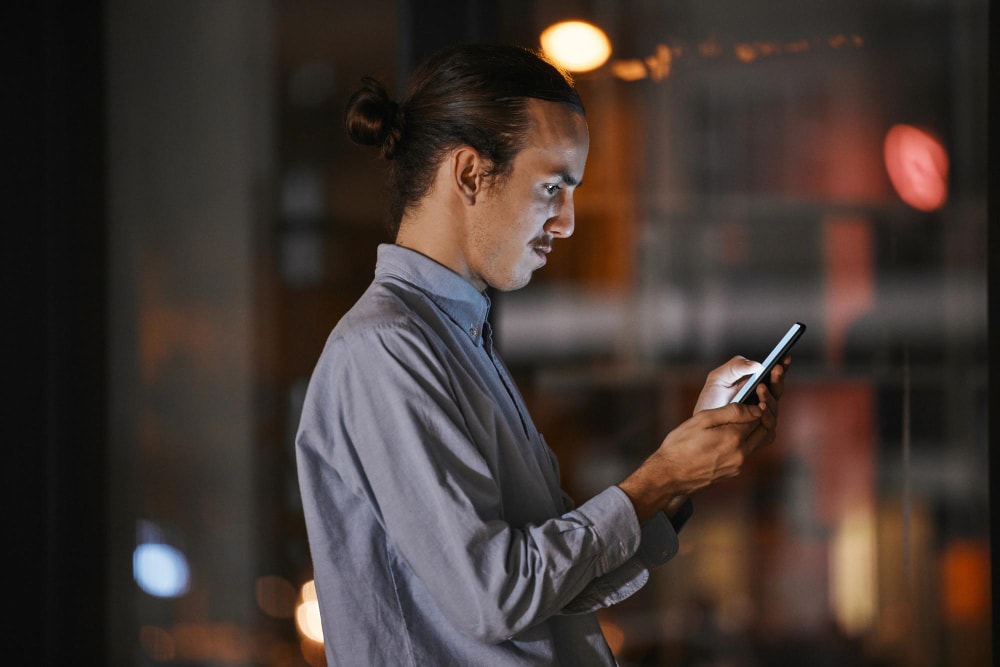 A business man in his office working and scheduling texts to his contact lists.