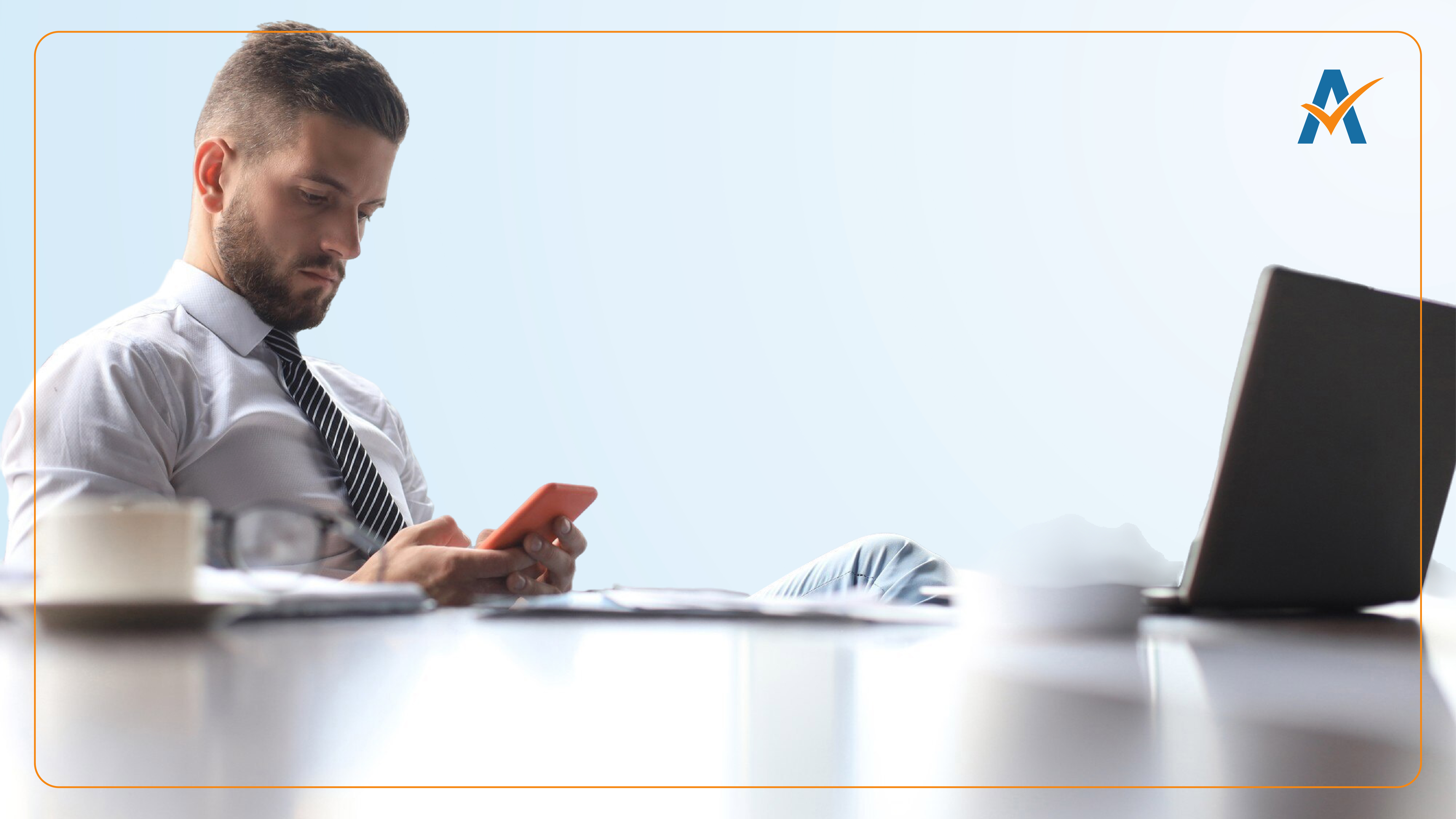 A professional man in a tie sits at a desk using a smartphone, with a laptop nearby. His focused expression suggests he’s reviewing data or communication performance, visually reinforcing the role of SMS marketing benchmarks in business strategy.