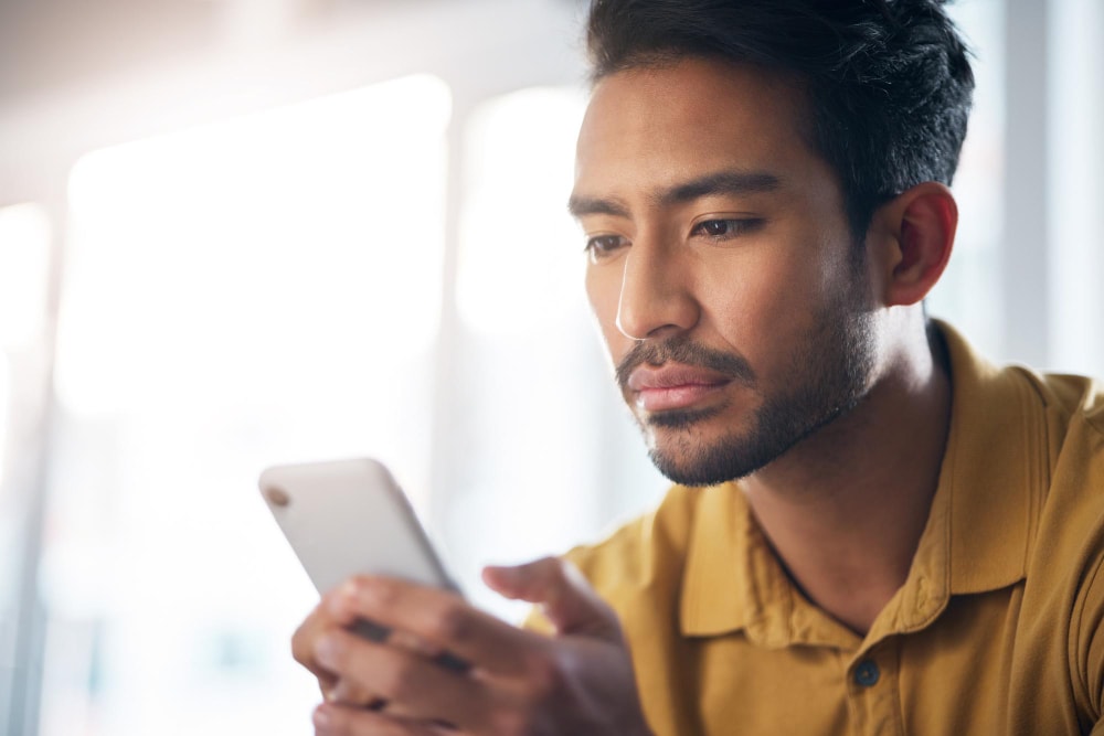 A man using his phone and two-way messaging through Teams with potential customers.